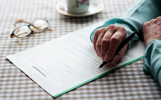 An elderly woman writes a euthanasia request. photo ANP, Roos Koole
