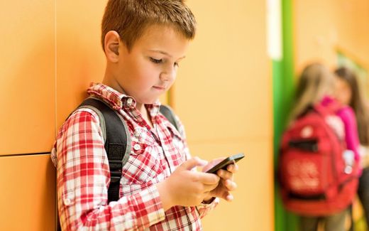 Primary school student is looking at his phone. Photo iStock 