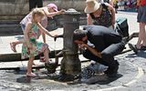 Tourists cool off and drink in a fountain. Photo AFP, Andreas Solaro