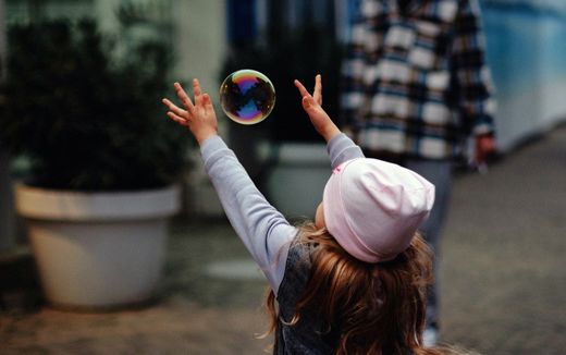 A child playing outside with bubbles. Photo Unsplash, Stas Ostrikov