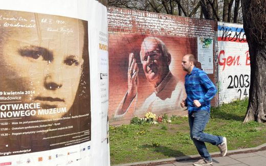 A man runs down a street in Krakow on 6 April 2014, past graffiti picturing the late Pope John Paul II and a poster for the opening of a Karol Wojtyla museum in his hometown Wadowice. Photo AFP, Janek Skarzynski