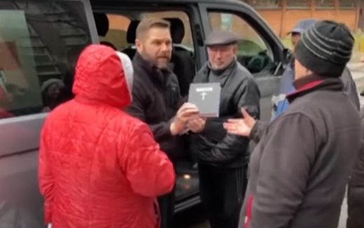 Anatoliy Raychynets hands out a Bible. Still from YouTube