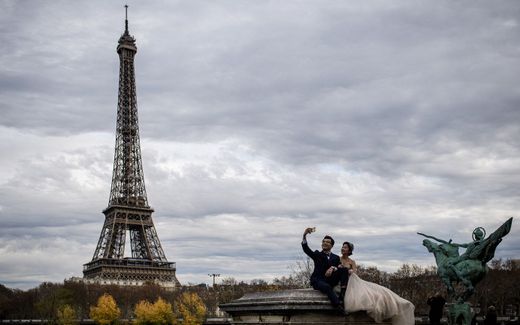 Newly weds take a selfie in front of the Eiffel Tower in Paris. Photo AFP, Philippe Lopez
