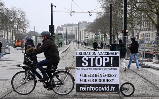 A man displays a banner, promoting the alleged conspiracy theory website 'reinfocovid', as he rides a bike during a rally to protest against the health pass and Covid-19 vaccines in Nantes, western France. Photo AFP, Damien Meyer
