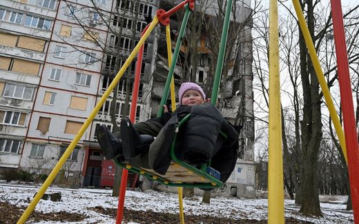 A child sits in a swing in front of an apartment block partially destroyed by shelling, in Ukrainian city of Kharkiv. Photo AFP, Sergey Bobok