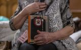 Anna from Lviv holds a bible and a rosary in the theatre of the Ukrainian House where a shelter for refugees is installed. Photo AFP, Wojtek  Radwanski