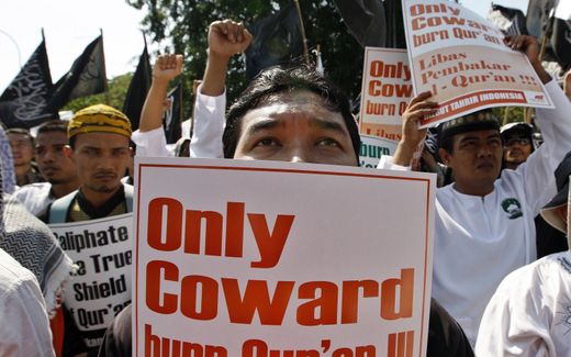 An Indonesian Muslim holds a placard reading 'Only Cowards burn the Quran' during a protest. Photo EPA, Mast Irham
