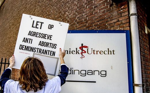 Employee of a Dutch abortion clinic hangs up a warning sign that reads: "Pay attention: Aggressive anti-abortion demonstrators". Photo ANP, Robin Utrecht