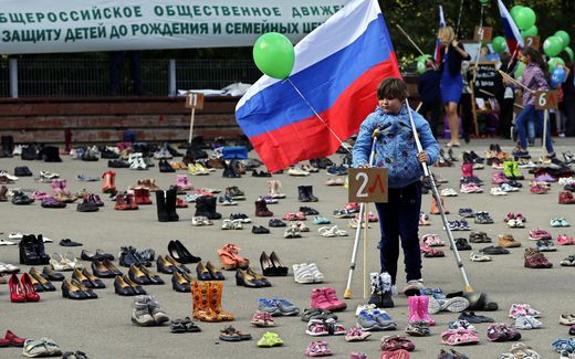 A girl holds Russian flag as she attends a public action themed, 'In defense of human life from the moment of conception (They could go to school)', in Moscow, Russia. Activists of the all-Russian public movement 'For Life' exhibit 2,000 pairs of children's shoes. Photo EPA, Yuri Kochetkov

/YURI KOCHETKOV