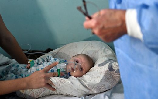 A woman holds an oxygen mask over the face of her baby. Photo AFP, Sergei Supinsky
