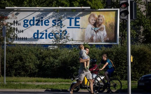 A man with a child on his arm crosses a street near a poster with the lettering reading ''Where are these children?' in Warsaw. The billboards, put up by a Catholic foundation last summer, were hard to miss: large and plastered all over Poland, they showed two little blonde girls in immaculate white posing in a wheat field -- along with the alarmist caption, "Where are these children?" Falling birth rate statistics displayed alongside in the form of a pictogram claim that the average Polish family had five children in the 1950s, down to three in the 80s and 1.5 today. Photo AFP, Wojtek Radwanski