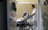 A healthcare professional takes and elderly lady in a wheelchair in the Hospice Department. Photo EPA, Peter Komka

