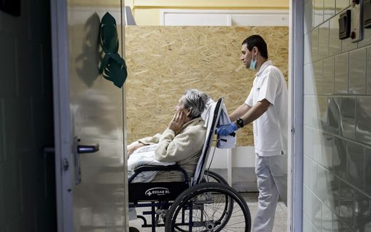 A healthcare professional takes and elderly lady in a wheelchair in the Hospice Department. Photo EPA, Peter Komka


