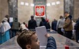 A child casts a parent's vote in the polling station at the Palace of Culture in Warsaw. Photo AFP, Wojtek Radwanski
