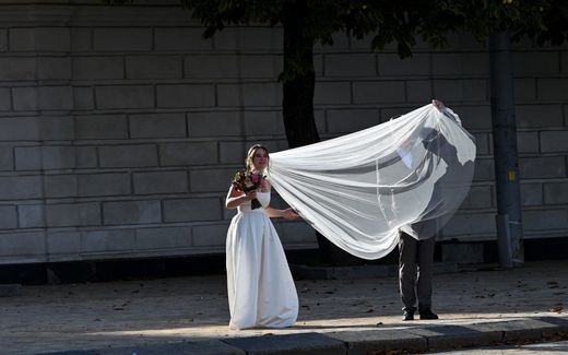 A bridegroom straightens his bride's  wedding veil. Photo AFP, Sergei Supinsky
