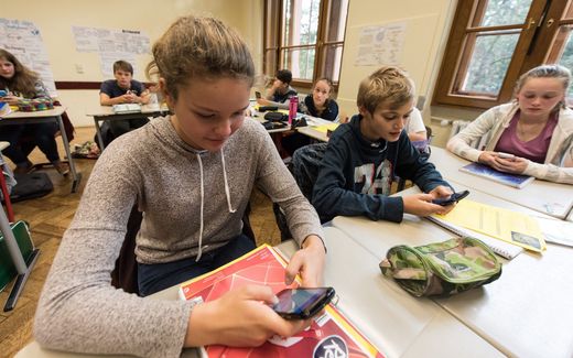 Students looking at their smartphones in the classroom. Photo EPA, Patrick Seeger