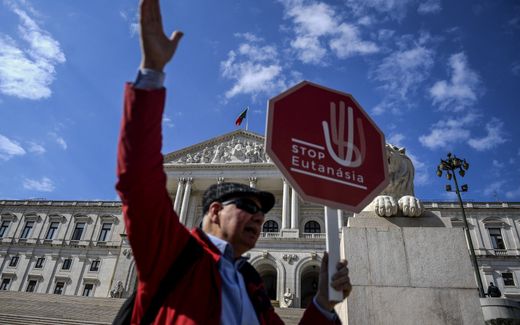 A man holds a stop sign reading "Stop Euthanasia" during a protest against the decriminalization of euthanasia in front of the parliament in Lisbon as lawmakers debate bills on euthanasia. Photo AFP, Patricia De Melo
