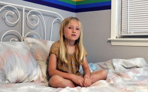 Girl sitting on her bed with a rainbow flag in the background. Potential foster parents in Norway learn how to deal with gender questions their foster children may have. Image not related to article. Photo AFP, Francois Picard

