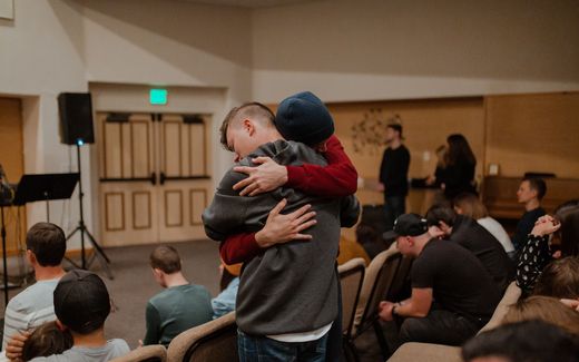 A young man is comforted during a church service. Photo Unsplash, adrianna geo 