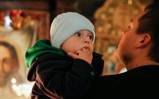 A father with his daughter in an Orthodox Church in Ukraine. Photo EPA, Sergey Dolzhenko