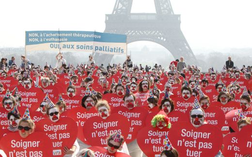 People take part in a flash mob event organized by the "Alliance VITA" association as part of their tour of France in solidarity with elderly people and against euthanasia. The placards read "To care is not to kill". Photo AFP, Kenzo Tribouillard