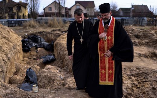 Priests at a mass grave in Bucha. Photo AFP, Ronaldo Schemidt
