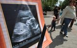 A pregnant woman and her child pass by a banner with an echography of a fetus during a rally against abortion in Moscow. Photo AFP, Alexey Sazonov