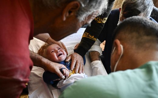 Members of the Muslim community comfort a child during a circumcision ceremony. Photo AFP, Nikolay Doychinov
