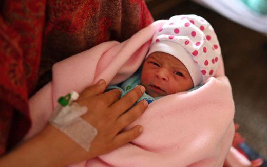 A mother holding her newborn daughter inside a maternity ward of a hospital. Photo AFP, Money Sharma 
