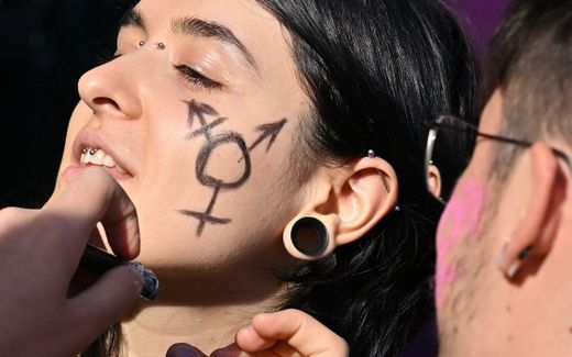 A young woman has her face made up with a gender symbol. Photo AFP, Alberto Pizzoli