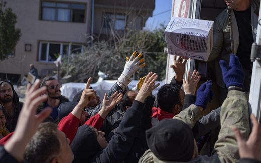 Residents grab food, clothes and household items delivered from the back of a truck in the Turkish city of Samandag. Photo AFP, Yasin Akgul

