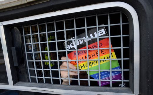 A Russian gay and LGBT rights activist shows sign reading "Love is stronger than homophobia" from inside of a Russian riot police van during unauthorized gay rights activists rally in cental Moscow. Photo AFP, Kirill Kudryavtsev  