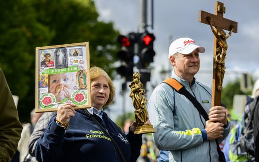 A protester displays a placard reading: "We love life" (L) as another one displays a crucifix during the annual anti-abortion "March for Life" demonstration in Berlin. The Roman Catholic Church in Germany is much more outspoken pro-life than the Protestant Church of Germany. Photo AFP, John MacDougall
