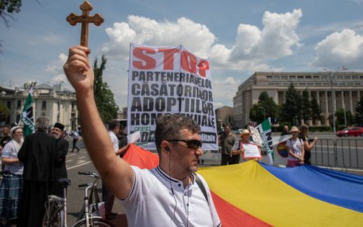 A demonstrator holds a Christian cross while others hold banners during a rally against gay marriage in Bucharest. The ruling of the ECHR will most likely meet much opposition among the Romanian population. Photo AFP, Illona Andrei

