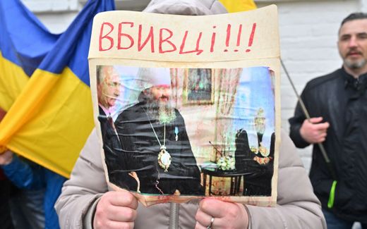 A woman holds picture depicting Metropolitan Pavlo, director of the Lavra, standing next to the Russian President Vladimir Putin and reading "Killers!!!" as they rally at the entrance to the Kyiv-Pechersk Lavra in Kyiv. The Kyiv Pechersk Lavra was inhabited by monks from the Ukrainian Orthodox Church, which is accused of collaboration with the Russian invaders. Photo AFP, Sergei Supinsky