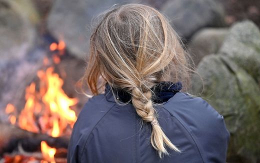 A girl sits next to a campfire at a forest camp on the outskirts of Ballerup, Denmark. Photo AFP, Sergei Gapon