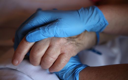 Nurse holding the hand of a patient in palliative care. Photo AFP, Pascal Pochard-Casabianca
