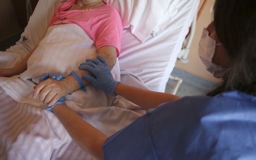A nurse holds the hand of a patient in the palliative care unit. Photo AFP, Pascal Pochard-Casabianca
