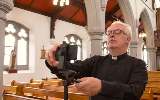A pastor in Scotland preparing his phone to record himself. Photo EPA, Robert Perry