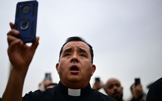 A priest records Pope's weekly general audience with his mobile phone at St Peter's square in The Vatican. Photo AFP, Tiziana Fabi
