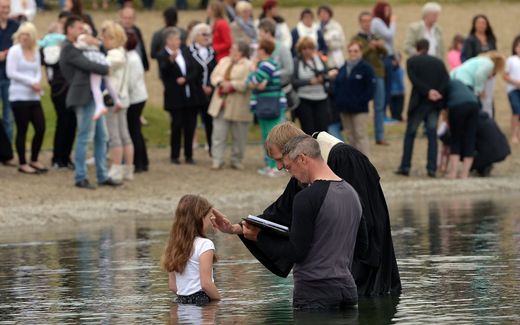 A Protestant pastor baptises a girl in the lake in Schladen, Germany. Image not related to article. Photo EPA, Peter Steffen