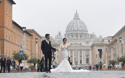 Wedding couple poses in Rome in front of the St Peters Basilica. Photo AFP, Tiziana Fabi