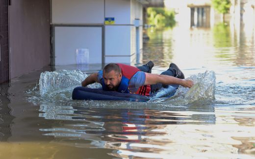 A local resident is seen on an inflatable mattress in a flooded area in Kherson on June 7, 2023, following the destruction of the Kakhovka hydroelectric power plant dam. Photo AFP, Olexander Kornyakov
