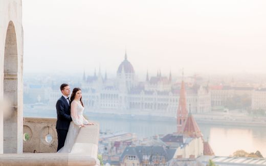 Couple in front of Danube river. On the other side of the river, the Hungarian parliament is visible. photo Freepik