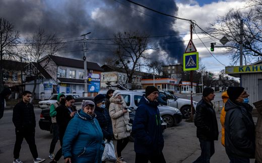 People stand in line in front of a supermarket while smoke billows over the town of Vasylkiv just outside Kyiv.  Photo AFP, Dimitar Dilkoff