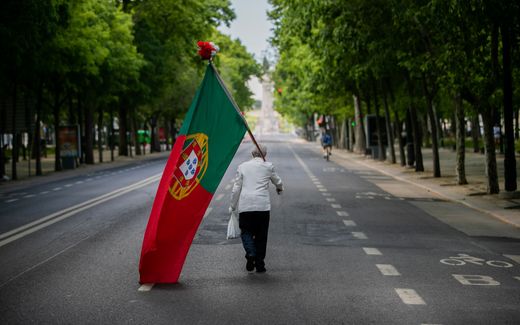 A man with a Portuguese flag walks along Avenida da Liberdade in Lisbon. photo EPA, Jose Sena Goulao