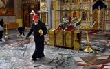 An Orthodox priest collects religous objects as others clear up glass and debris inside a cathedral damaged after missile strikes. Photo AFP, Andriy Andriyenko